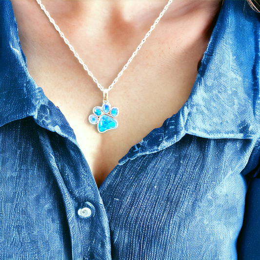Close-up of Angel Paws pet memorial necklace on a model in sterling silver, featuring blue opal cremation stones