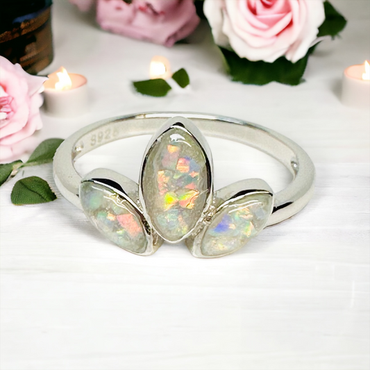 Closeup of the Tiara 3 Stone Breastmilk / Cremation Ring in Sterling Silver, displayed on a table, featuring marquise-shaped pearl white crushed opal stones, with the largest in the center, symbolizing a cherished connection.
