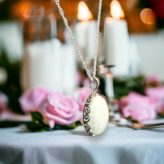 Side view of the Eternal Grace oval filigree pendant in sterling silver, showcasing the intricate craftsmanship and delicate silver chain, emphasizing the elegance of breastmilk/cremation ash jewelry.