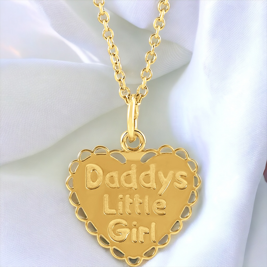 14K yellow gold heart necklace with 'Daddy's Little Girl' inscription, draped over a soft, white fabric.