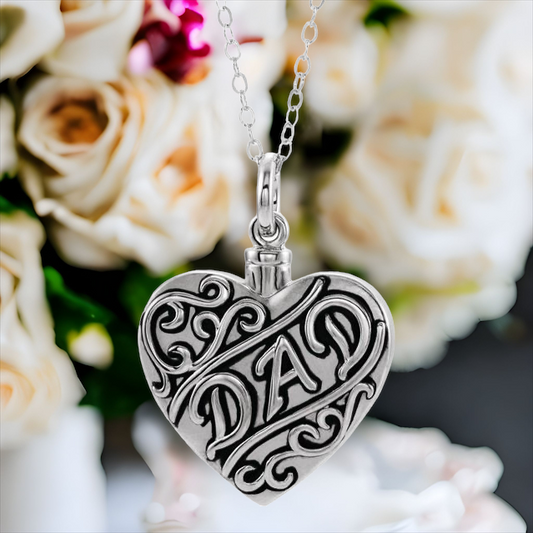 This beautiful dad cremation ash necklace for women is the perfect keepsake to remember a father who has departed. Antiqued scroll design on front of heart. "Dad" on the front center. Sterling Silver pendant.