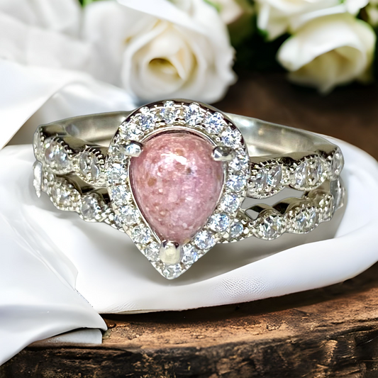Pink cremation cabochon in a teardrop ring set with a halo of shining gemstones all around. Perfect for breastmilk or cremation ash. Available in sterling silver. 